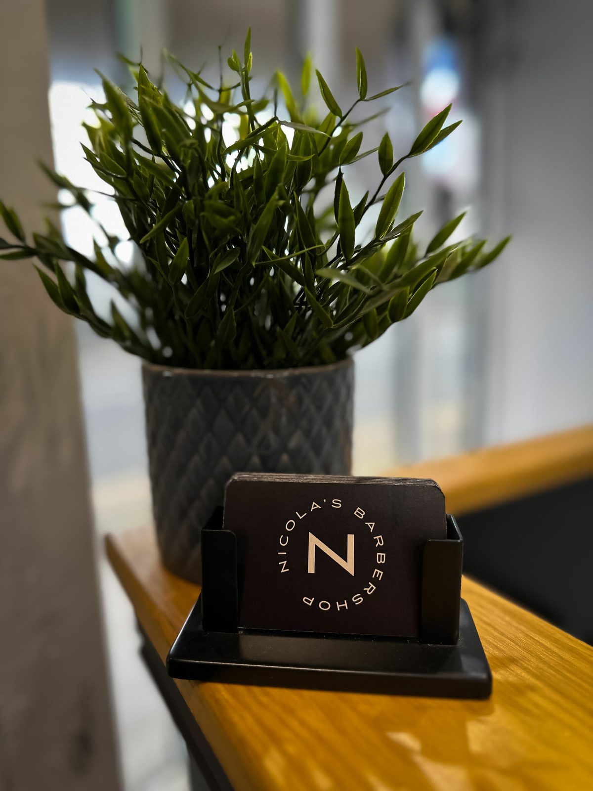 Nicola’s Barbershop business cards and plant on the counter