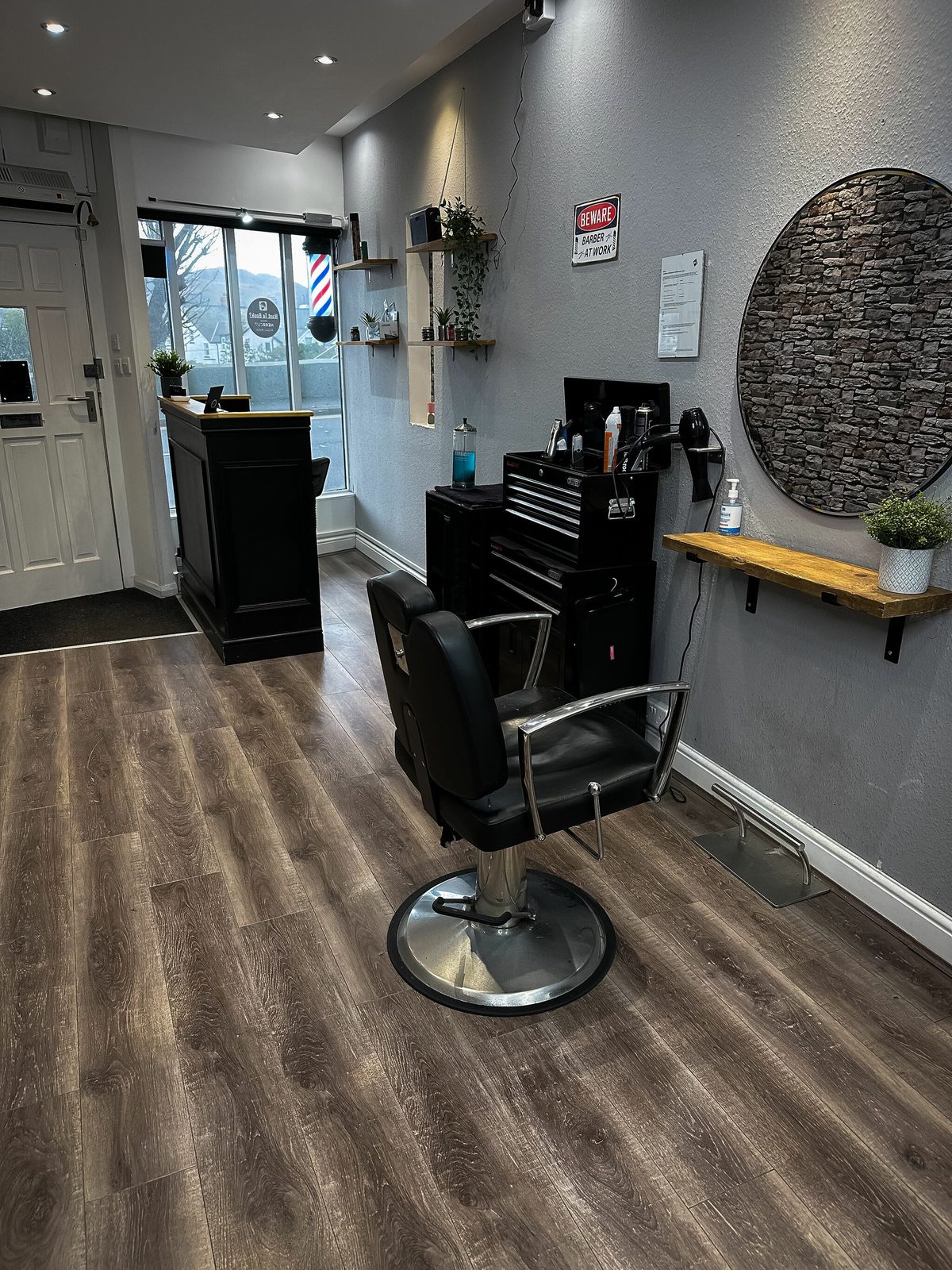 Barber station with circular mirror and tool chest near the front of the shop