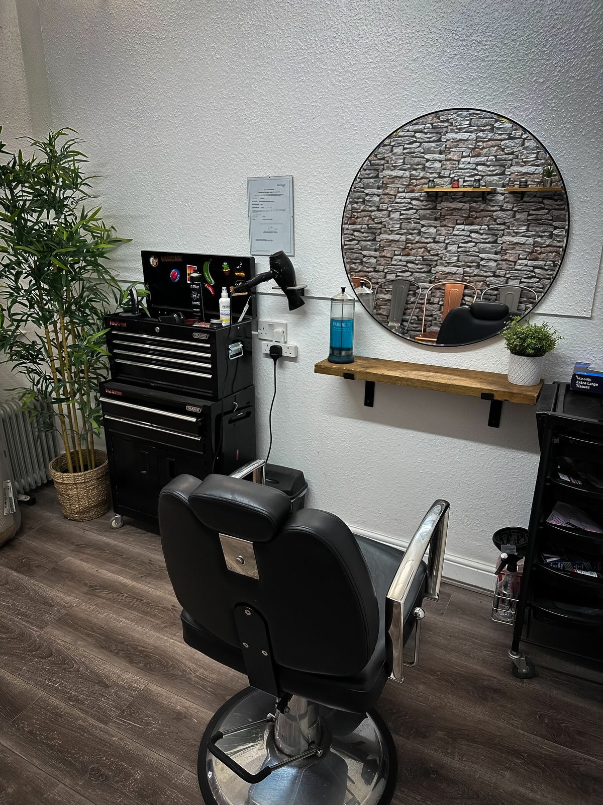 Barber chair and circular mirror with wooden shelf and bamboo plant