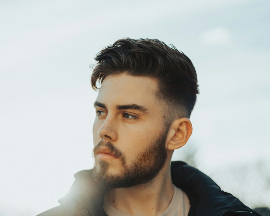 Man with a clean skin fade and short beard in a plain portrait